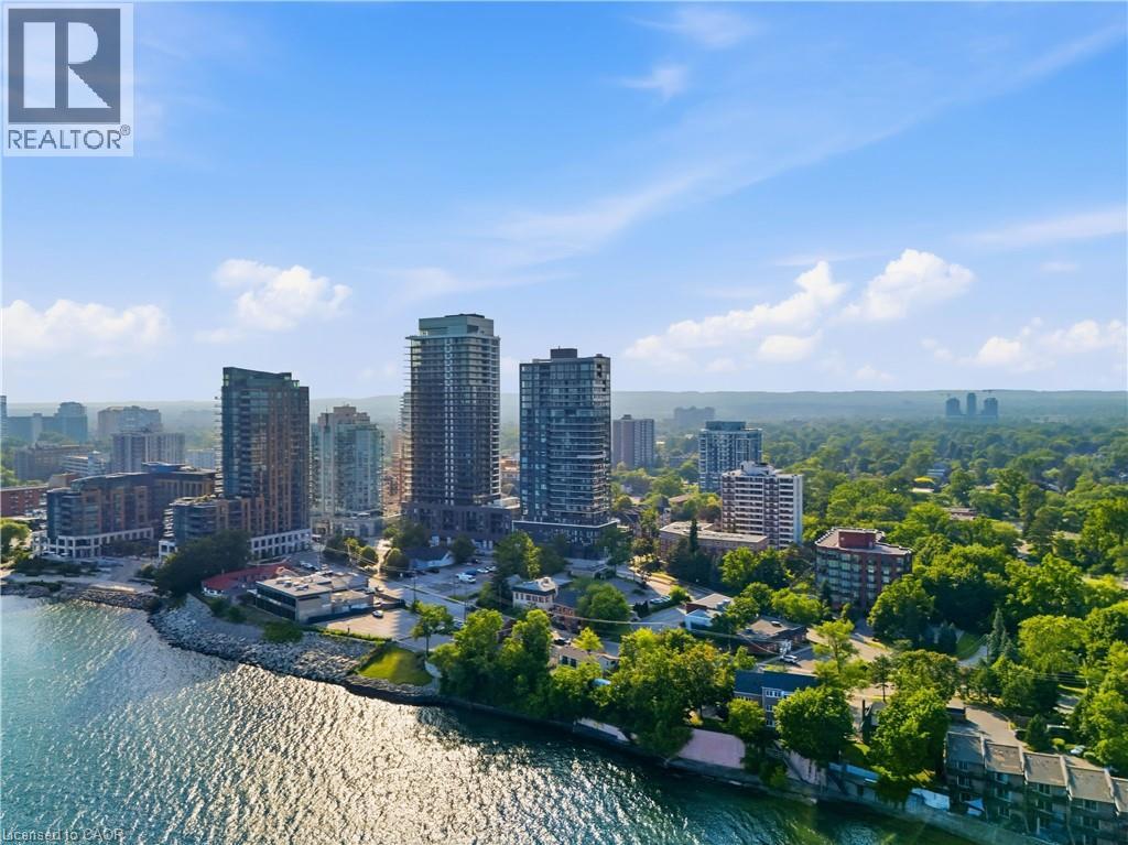 Urban waterside setting featuring multiple high-rise buildings, extensive tree canopy, and a prominent body of water