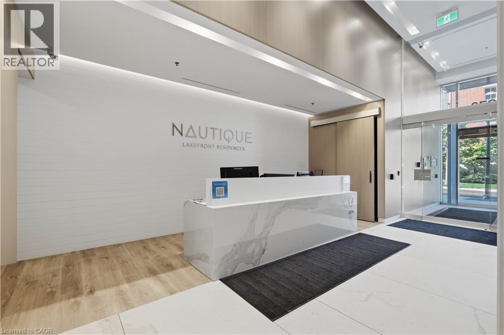 Modern reception area featuring a white stone-finish desk with veining, wood-finish flooring, white tile flooring, and recessed lighting