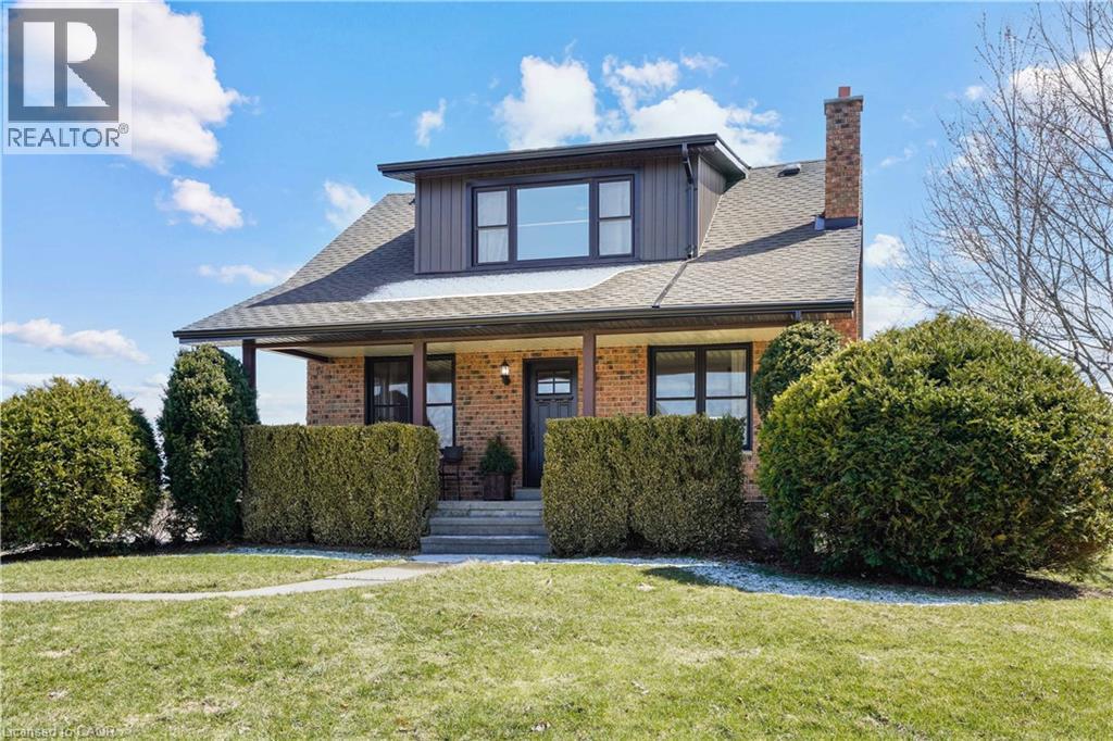View of front of home with a front yard, covered porch, brick siding, and a shingled roof