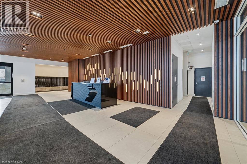 Lobby featuring a wood-finish slatted ceiling, coordinating wood-finish slatted accent wall with integrated vertical lighting, a dark polished reception desk, and light-toned tile flooring