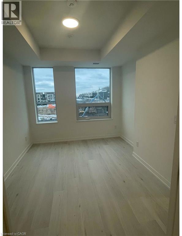 Spacious room featuring two large windows, light wood-finish flooring, recessed ceiling lighting, and white baseboards