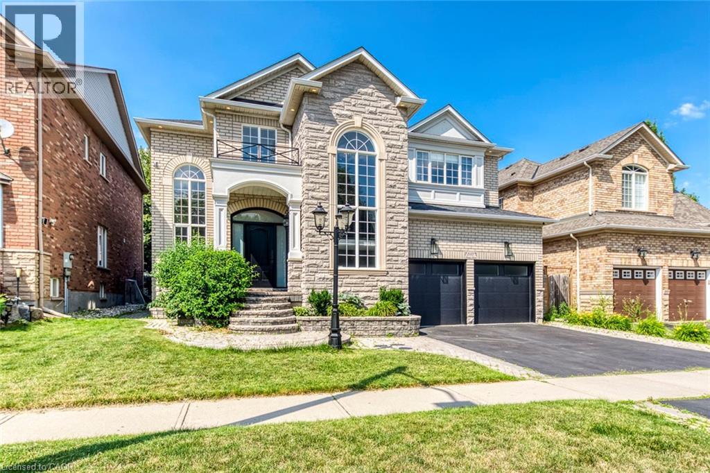 Stone and brick facade residence featuring a double car garage with black doors, an arched entry, and a prominent arched window
