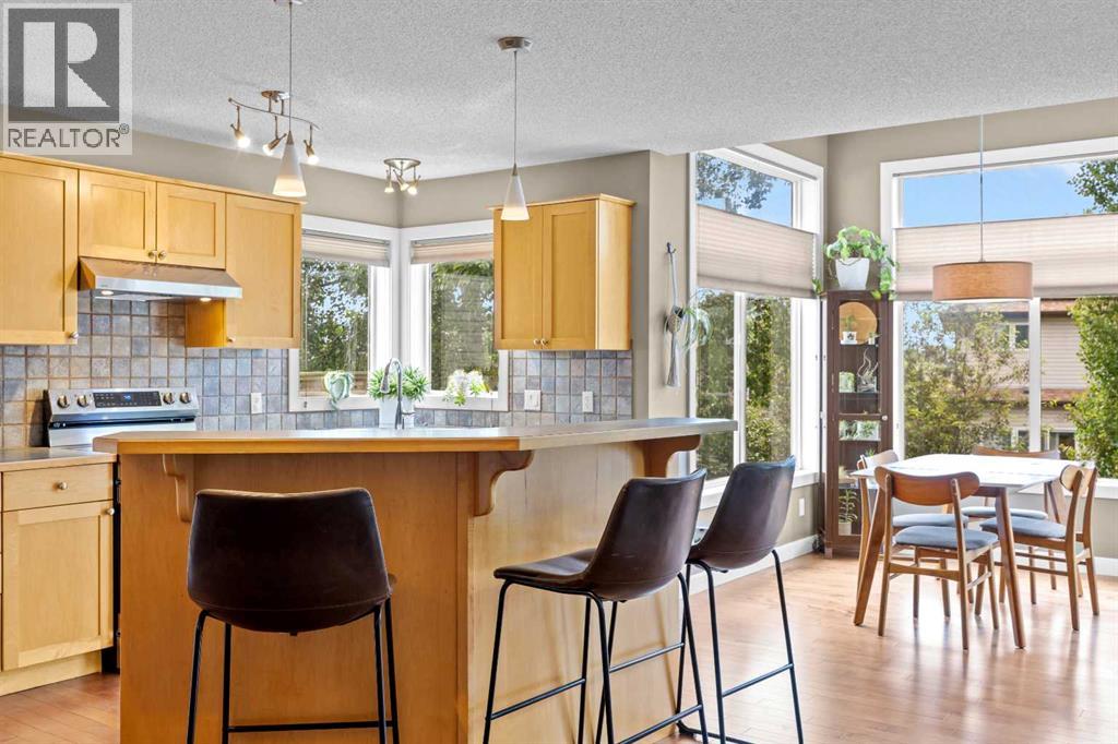 From the breakfast bar, the kitchen opens straight into a dining nook wrapped in windows — the sightlines here mean nobody ever eats alone