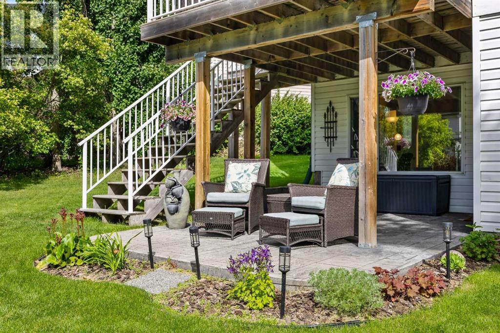 The walkout opens onto a covered stamped stone patio — shaded seating, garden views, and a quiet spot that works rain or shine