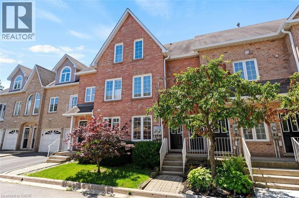 Brick facade townhome with a peaked roofline, white-framed windows, and a dedicated entrance with steps and white railings