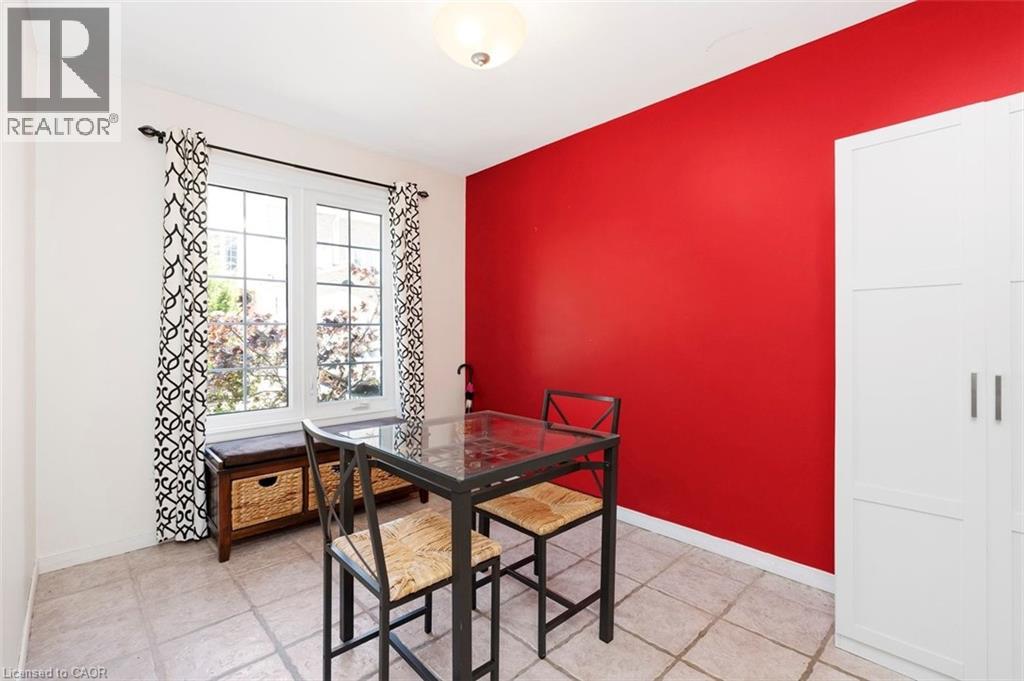 Spacious room featuring neutral-toned tile flooring, a large window with multiple panes, a bold red accent wall, and a built-in white storage cabinet with panel detailing and silver hardware