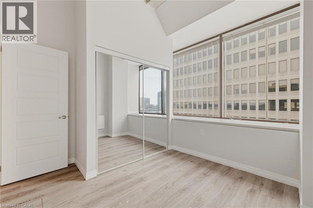 Expansive window wall with roller shades, light wood-finish flooring, white paneled door, and mirrored closet doors