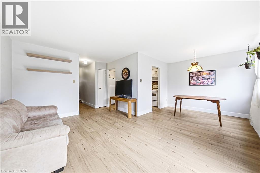 Open-concept living area with light-toned wood-finish flooring, white baseboards, and neutral wall paint