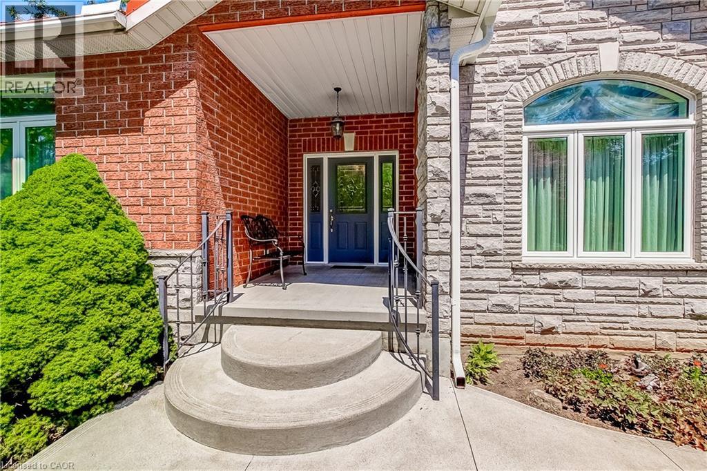 Inviting front entrance with a dark blue door and sidelights, featuring a concrete porch and steps with wrought iron railings
