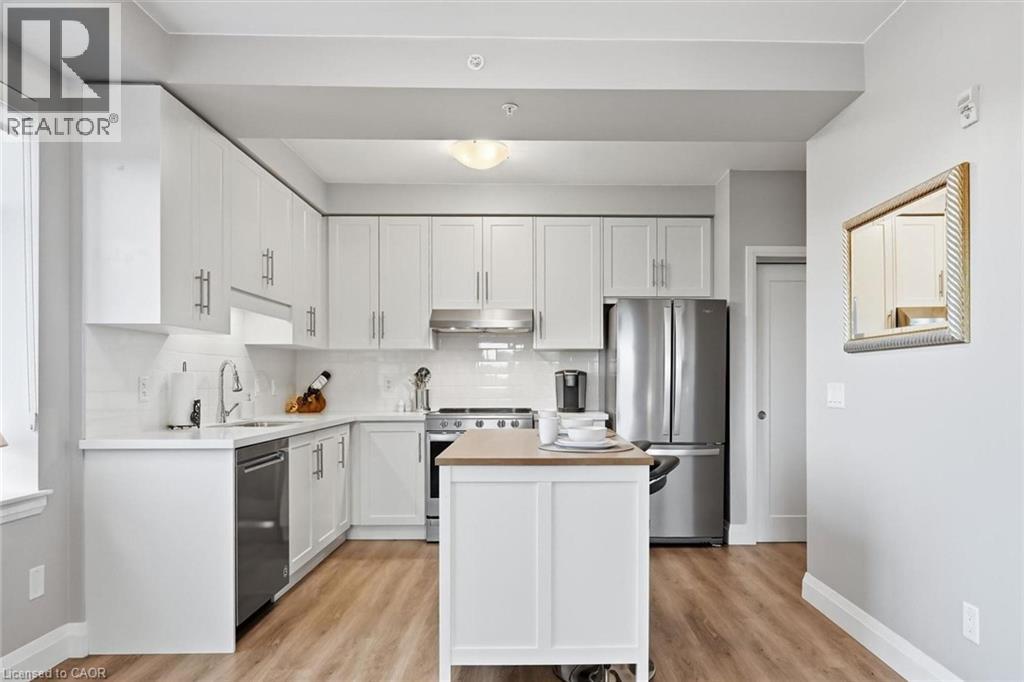 Modern kitchen featuring white cabinetry, stainless steel appliances, wood-finish flooring, and a central island with a wood countertop