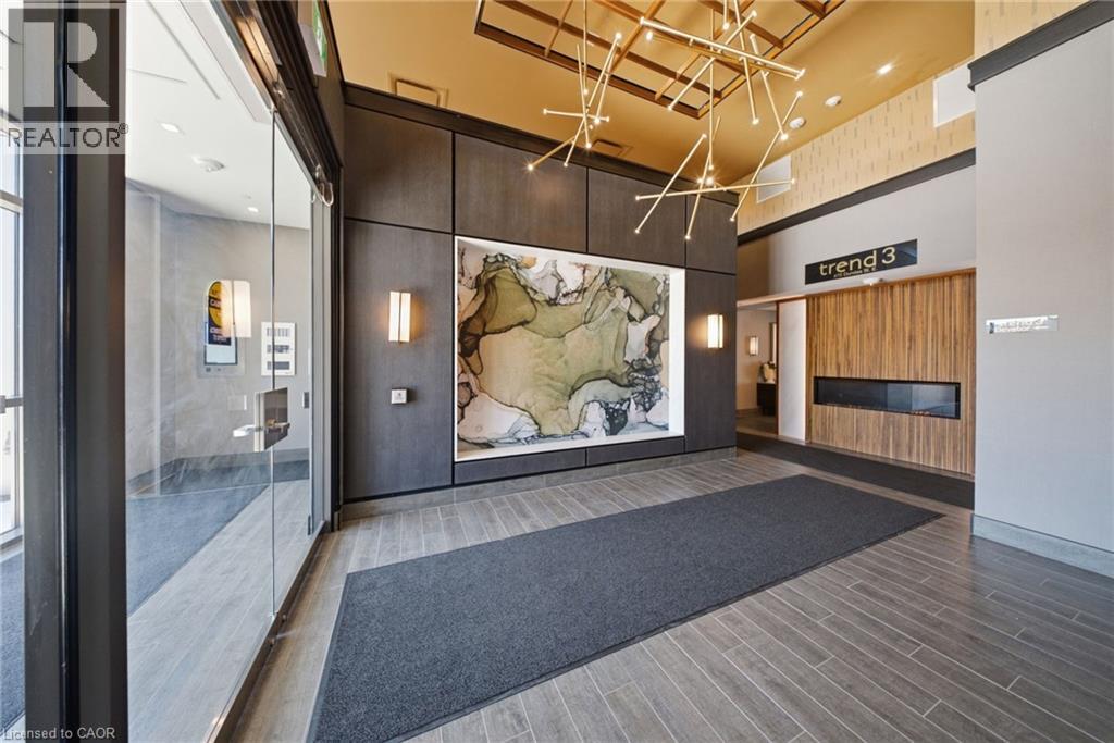 Modern entryway featuring sleek wood-finish paneling, a linear fireplace, and a contemporary chandelier