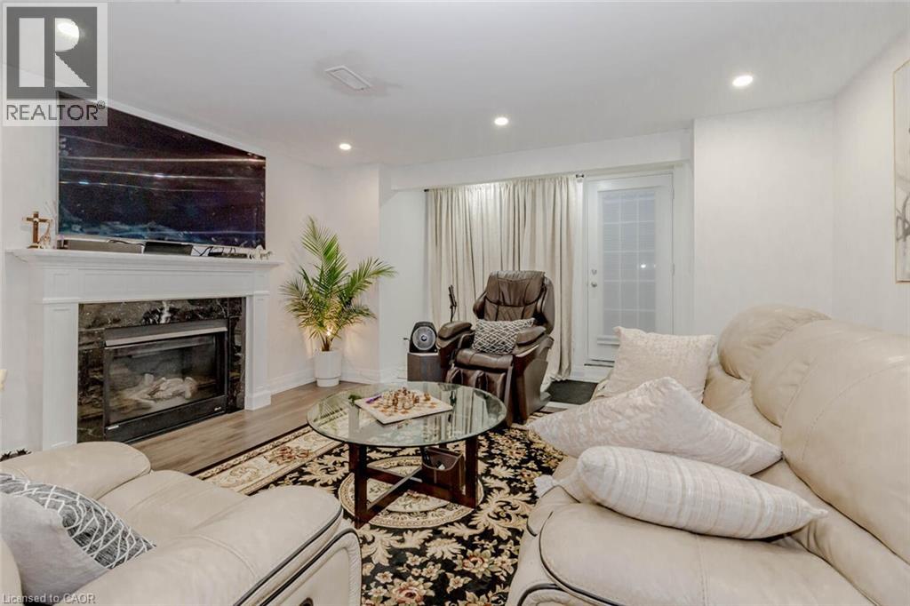 Living area featuring a fireplace with a white mantel and dark stone surround, recessed lighting, wood-finish flooring, and a glass-paneled door