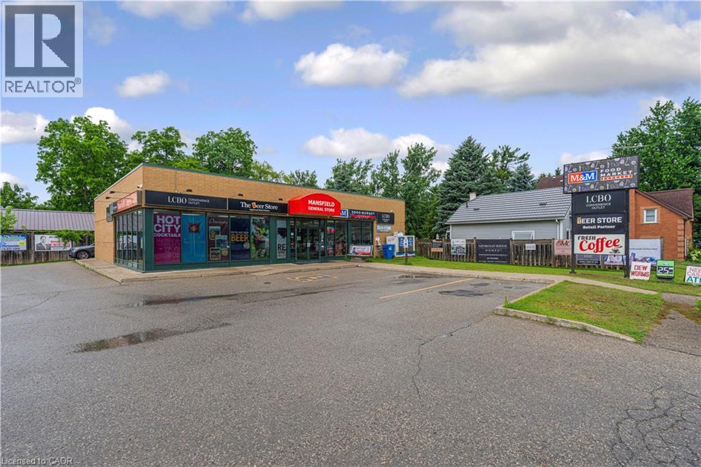 Commercial building featuring brick exterior with large storefront windows and an expansive paved parking area