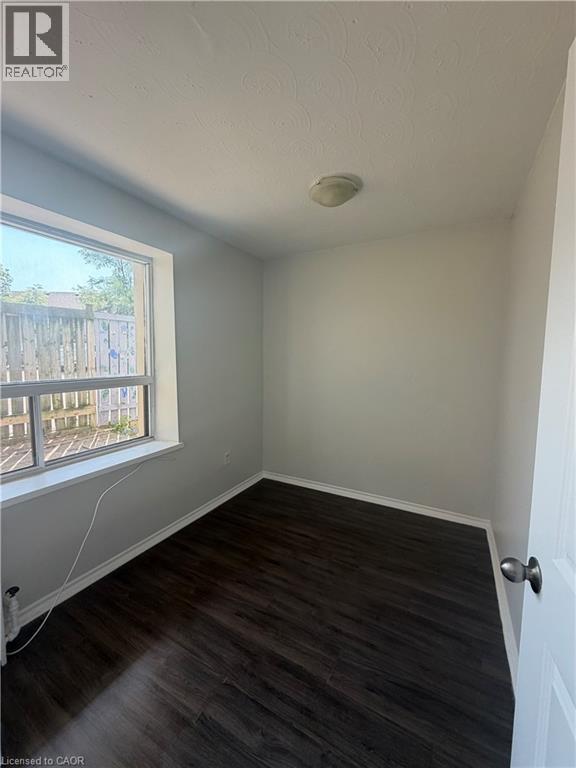 Compact room with dark wood-finish flooring, white baseboards, and neutral wall paint