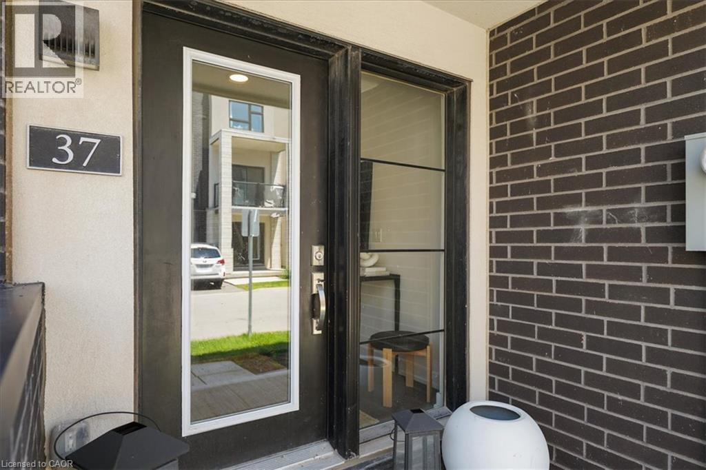 Modern entry featuring a black door with a full-length glass insert, a dark brick exterior, and a contemporary house number plaque