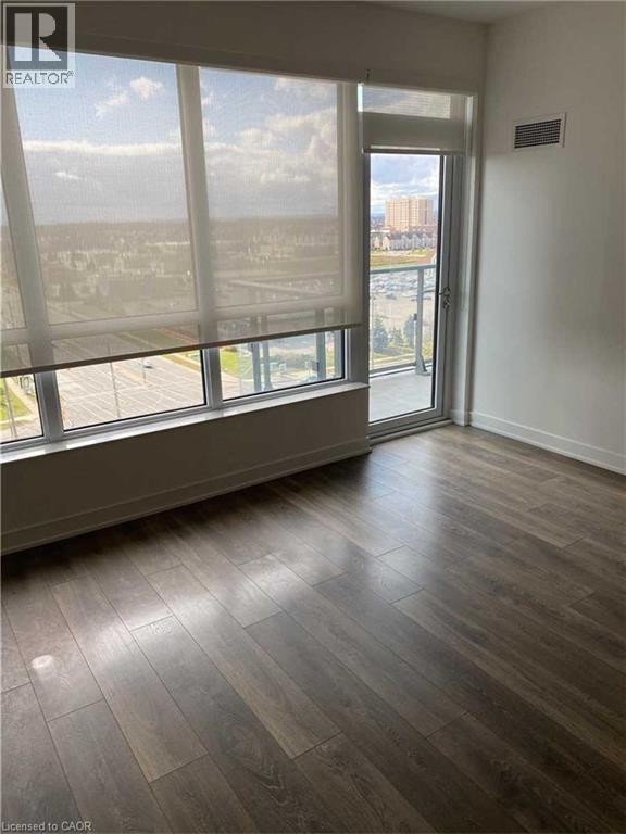 Bright room featuring expansive windows with roller shades, a balcony door, and wood-finish flooring