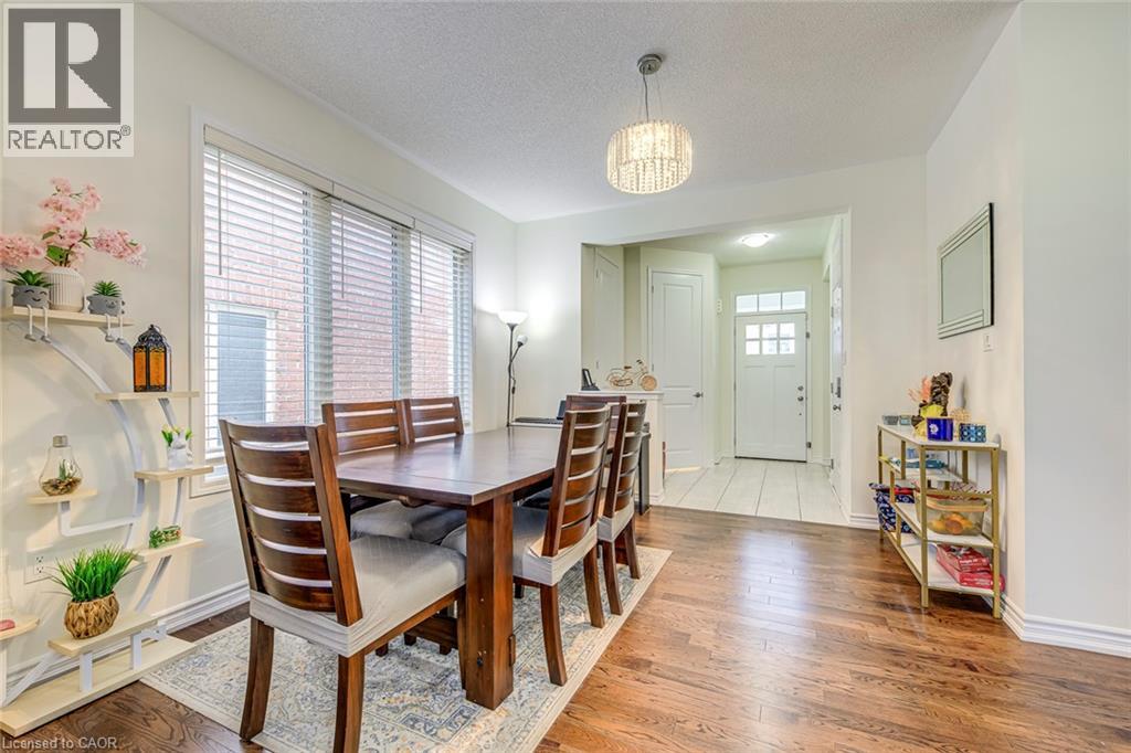 Dining area featuring wood-finish flooring, a contemporary chandelier, and a large window with horizontal blinds