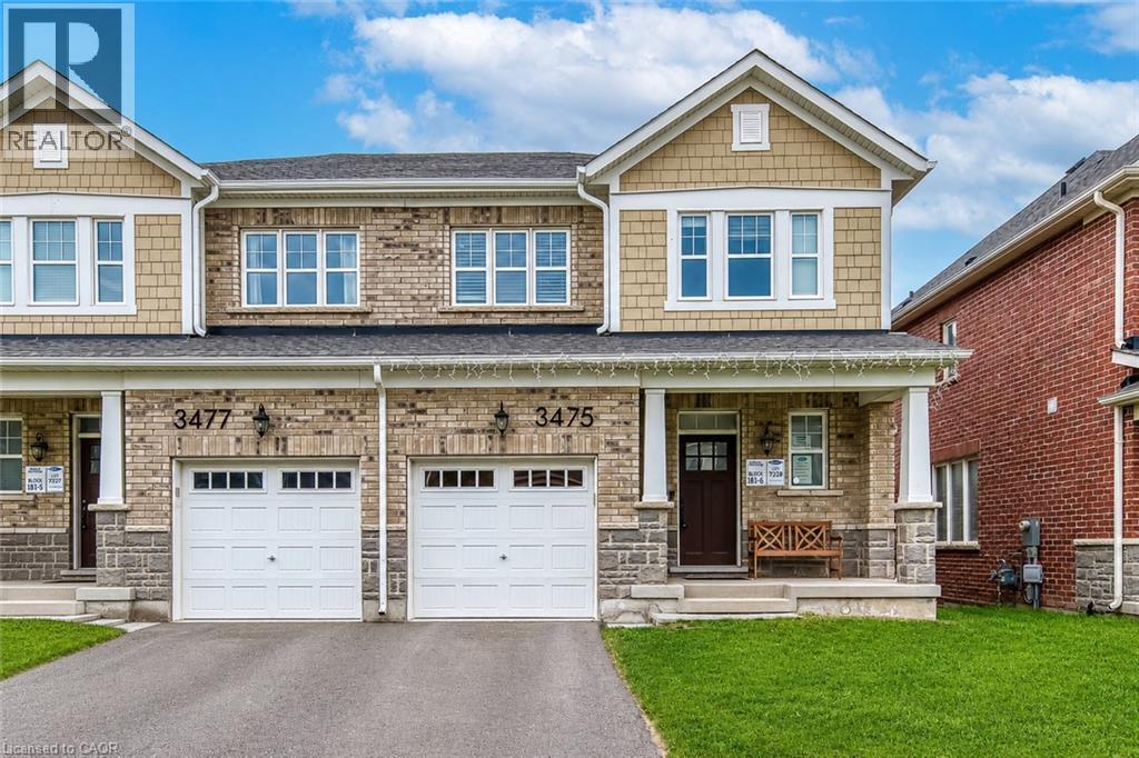 Brick and stone facade townhome with two separate garage bays, individual driveways, and a covered porch entry