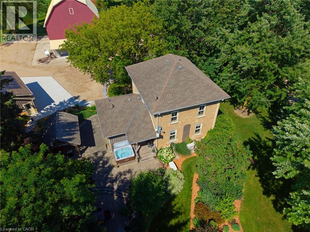Aerial perspective showcasing a brick residence with a gabled roof and surrounding mature trees