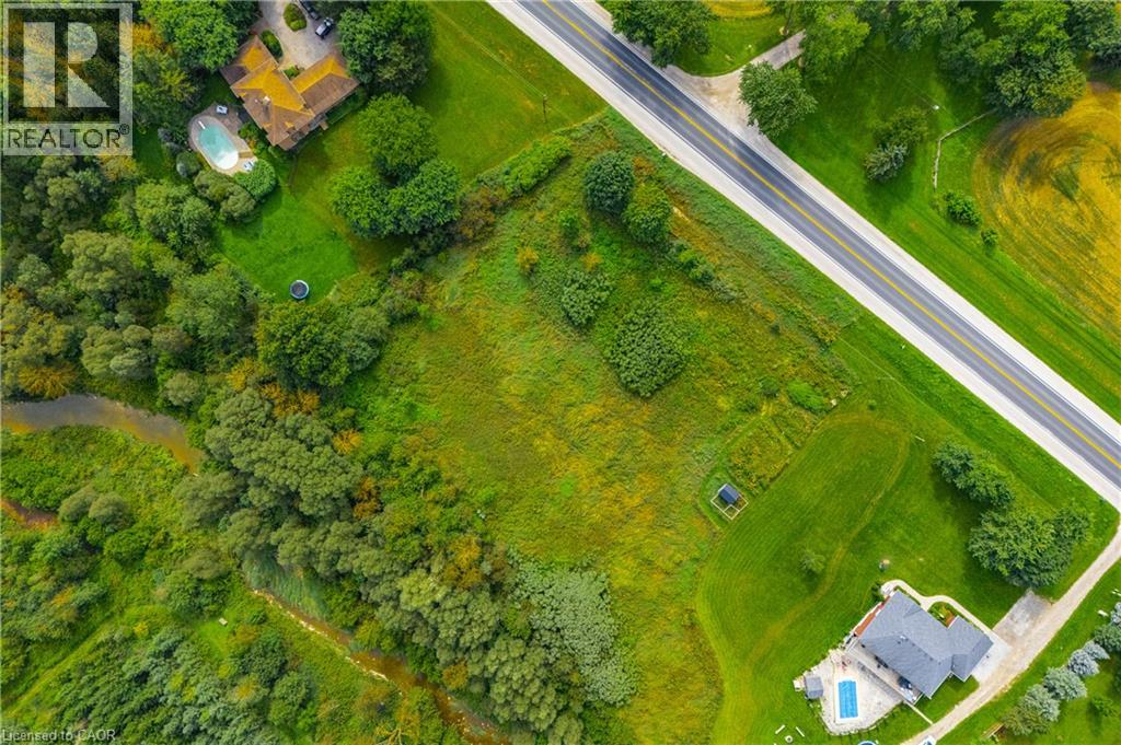 Expansive property featuring a paved road frontage, extensive green space, a winding creek, and mature tree lines