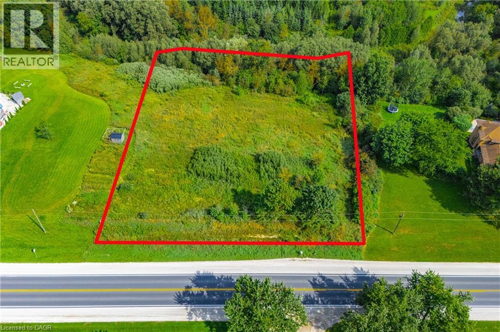 Expansive land parcel featuring a mix of cleared and treed areas, bordered by a paved road