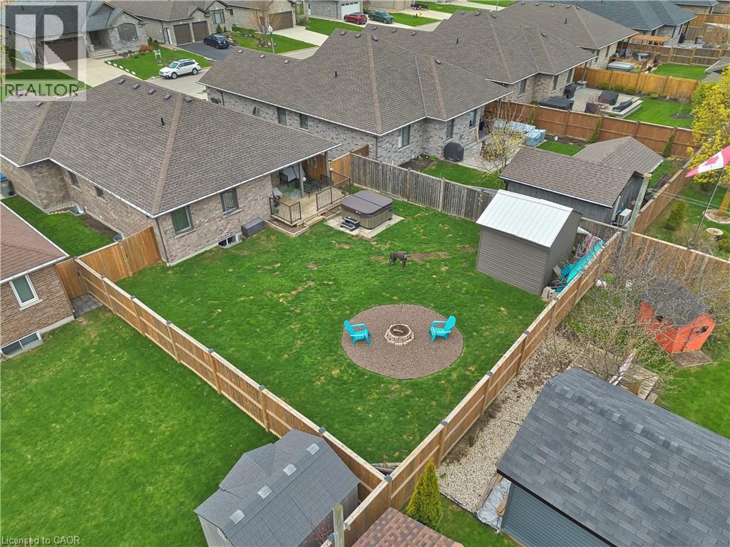 Expansive backyard featuring a manicured lawn, full perimeter fencing, and a dedicated fire pit area