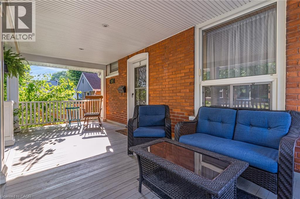 Covered front porch featuring a white spindle railing and wood-finish flooring
