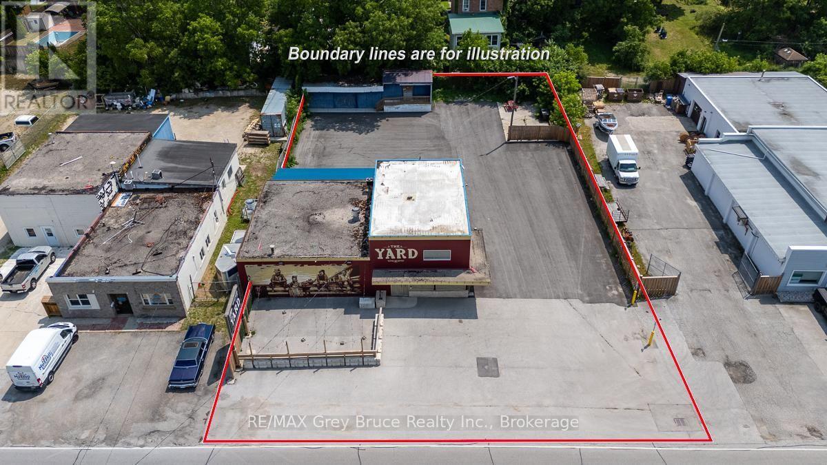 Paved parking lot fenced on 3 sides