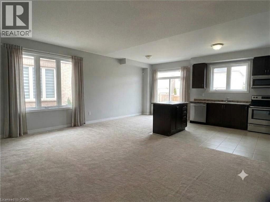 Open-concept living space featuring light-colored carpeting throughout the main area and tile flooring in the kitchen