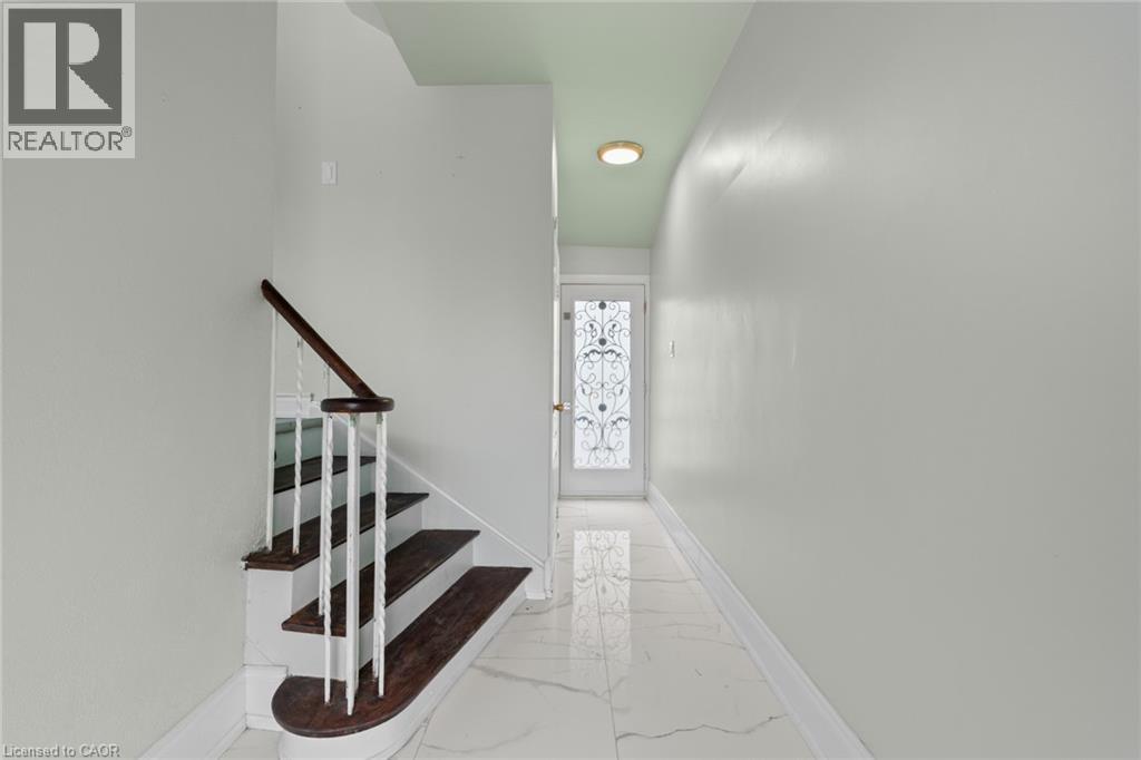 Foyer featuring a decorative glass panel entry door, white marble-look tile flooring, and a staircase with wood treads and a dark wood handrail