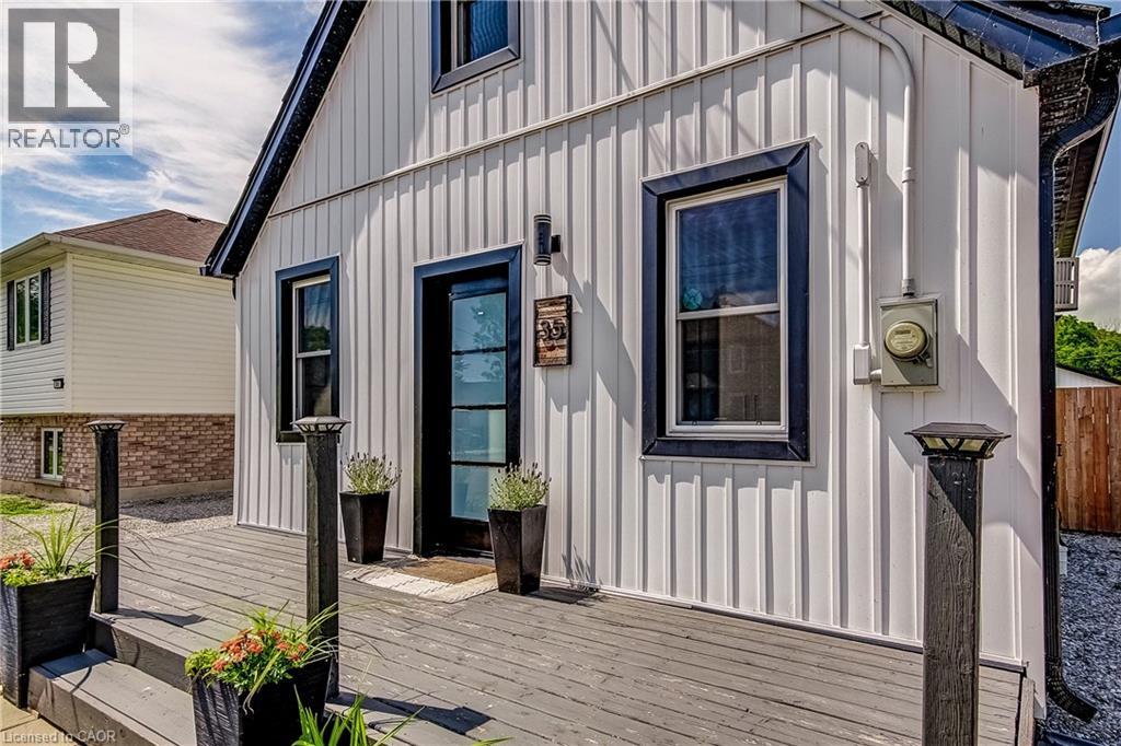 White board and batten siding with dark trim windows and a dark-framed glass paneled entry door