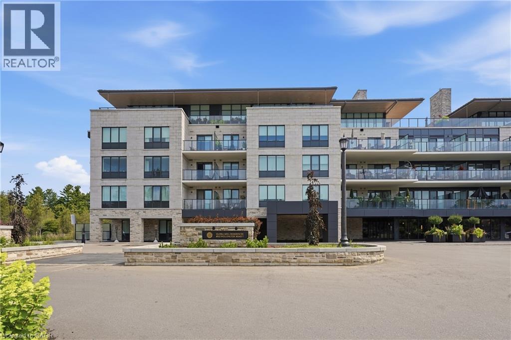 Contemporary multi-story building featuring light-colored stone facade, multiple private balconies with glass railings, large windows, and a prominent stone-clad entrance monument