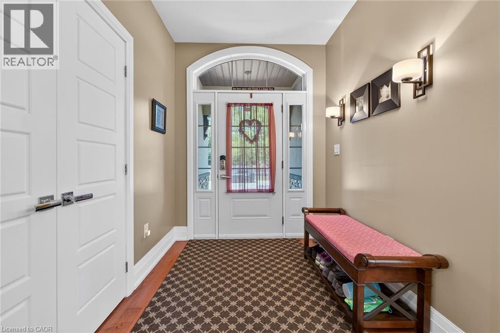 Entryway featuring an arched transom over a glass-paneled door, sidelight windows, a textured area rug, wood-finish flooring, and wall sconces