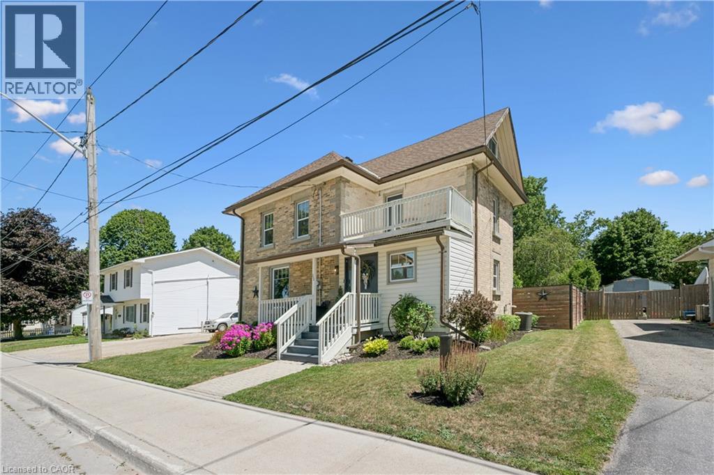 Multi-story residence featuring a brick and siding exterior, a second-story balcony, and a covered front porch