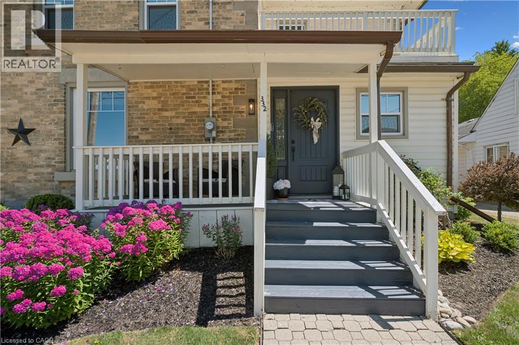 Welcoming front entrance featuring a brick and vinyl exterior with a covered porch, white railings, and composite paver walkway