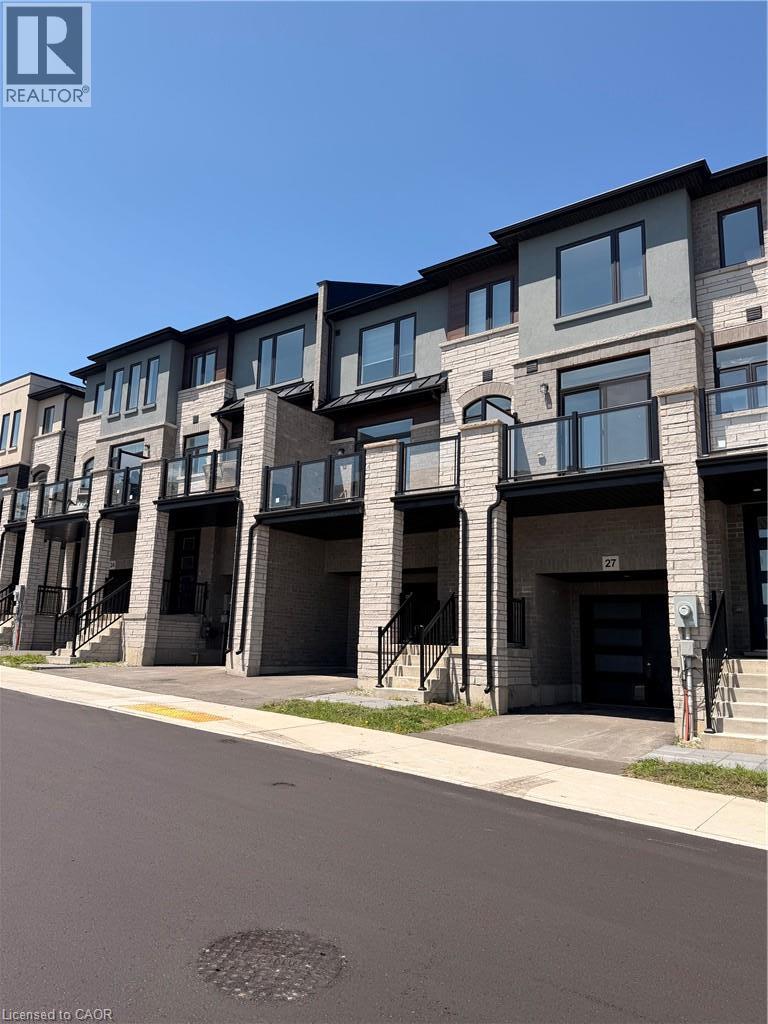Modern townhome row featuring sleek brick and stone exterior with black aluminum-framed windows, multi-level architecture with staggered rooflines, integrated garage entries with black doors, and cont