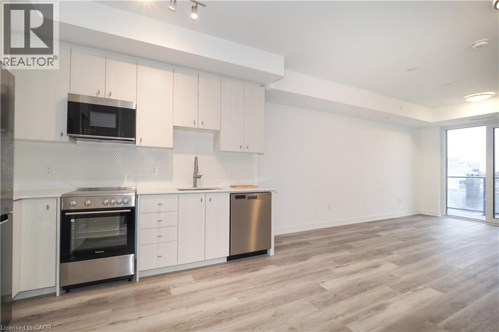 Contemporary kitchen featuring white cabinetry, stainless steel appliances, and a white hexagonal tile backsplash