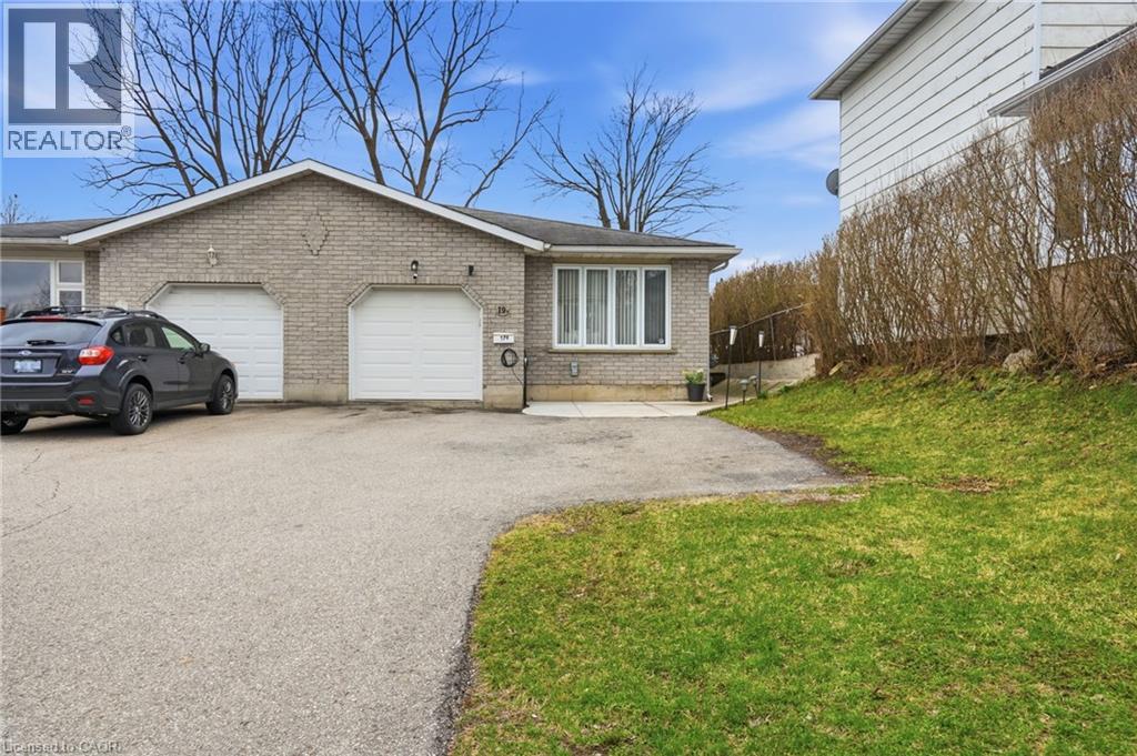 View of front of home with brick siding, asphalt driveway, an attached garage, and a front lawn