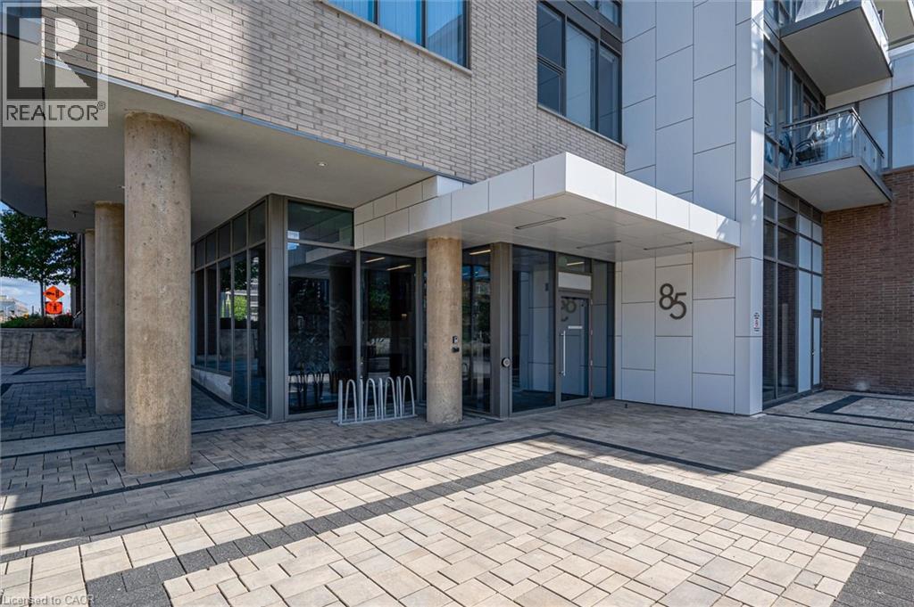 Contemporary building entrance featuring a prominent awning, large format numerical address, and a mix of brick and panel siding