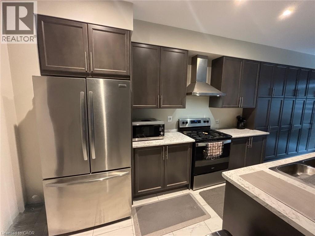 Modern kitchen featuring extensive dark wood-finish cabinetry, stainless steel appliances, speckled countertops, and a double basin sink