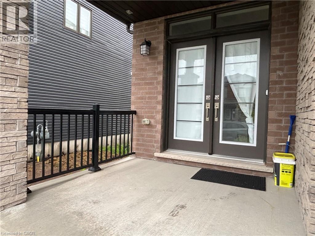 Entry porch featuring brick and stone veneer accents, dark double entry doors with integrated glass panels, and a black metal railing