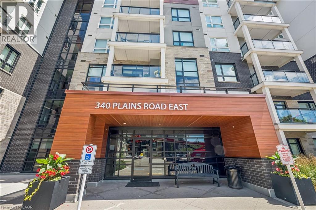Modern building exterior featuring a wood-finish entrance canopy, dark brick accents, and stone facade