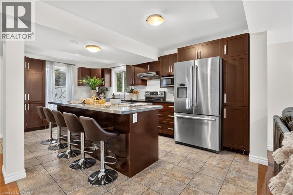 Kitchen featuring wood-finish cabinetry, stainless steel appliances, a center island with seating, and tile flooring