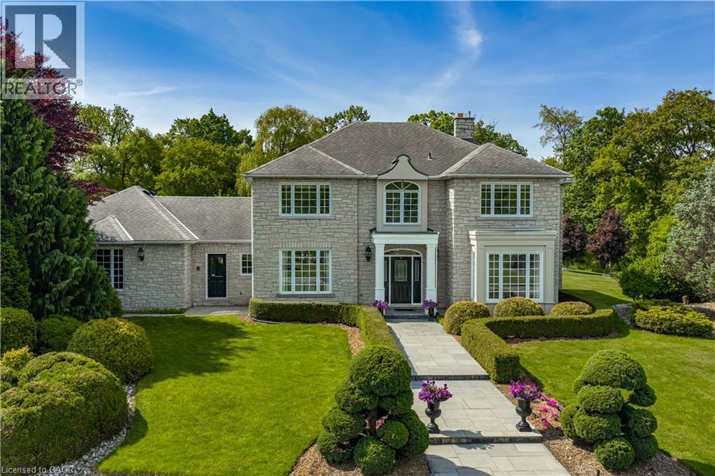 Stone exterior, multi-pane windows, a prominent entryway, a stone pathway, and mature landscaping