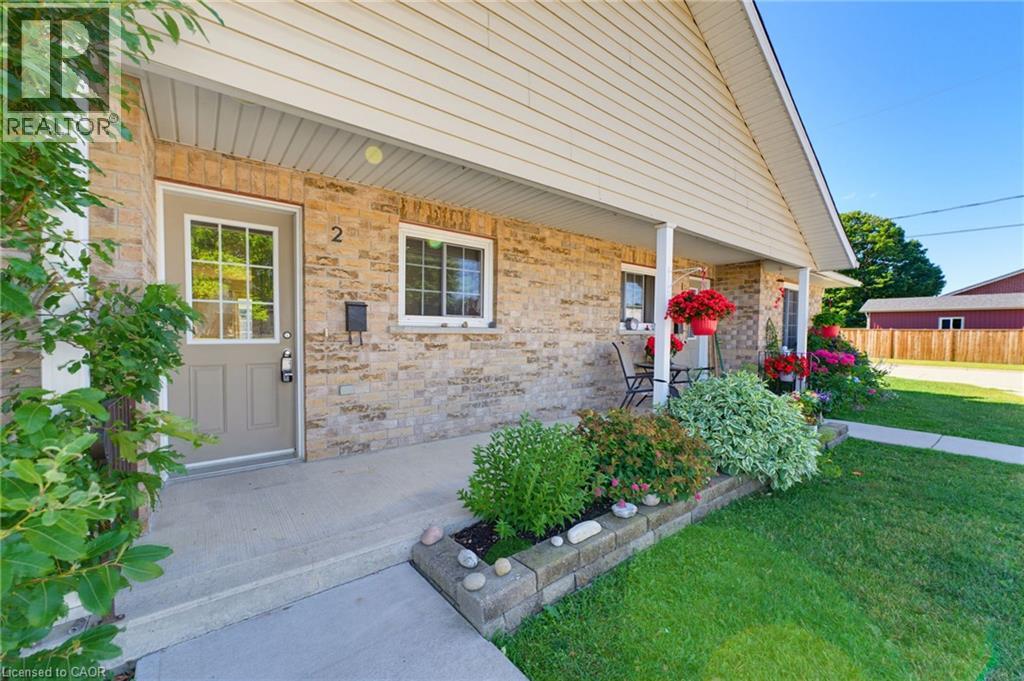 Brick exterior with siding accents, covered front porch, concrete walkway, and landscaped planter box with stone retaining wall