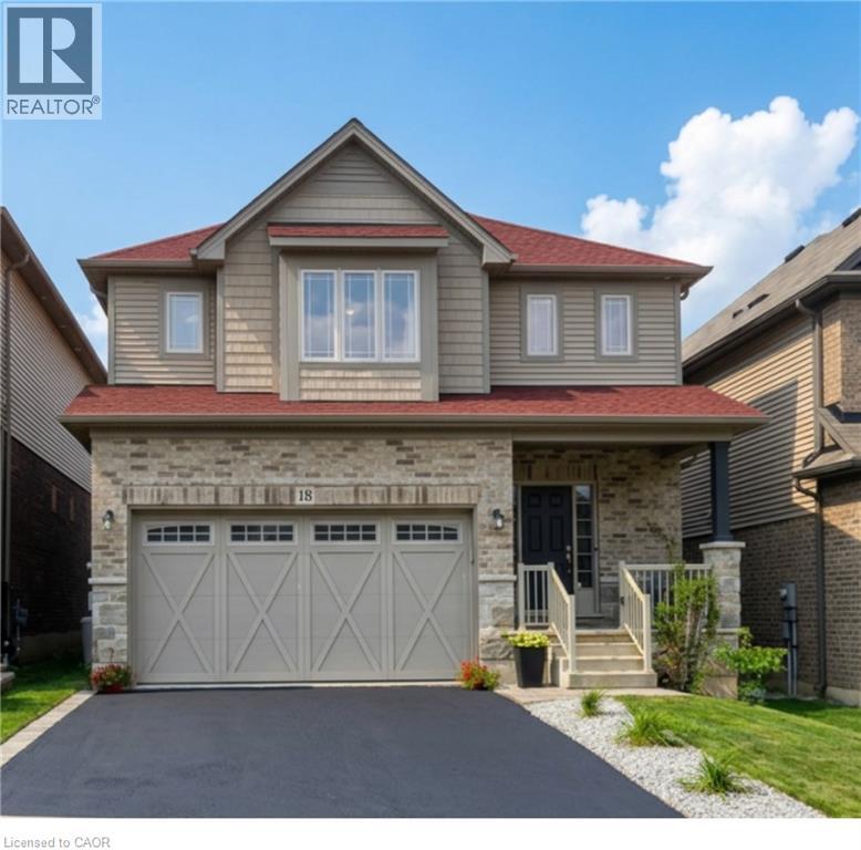 Two-story residence featuring a red roof, a stone and siding facade, an attached two-car garage with decorative doors, a paved driveway, and a covered front porch with steps