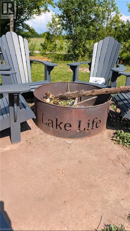 Outdoor fire pit with a custom ""Lake Life"" cut-out design, surrounded by gray Adirondack chairs