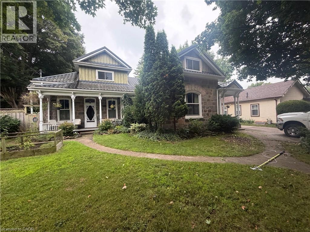 Stone exterior with decorative trim, covered porch, and mature landscaping