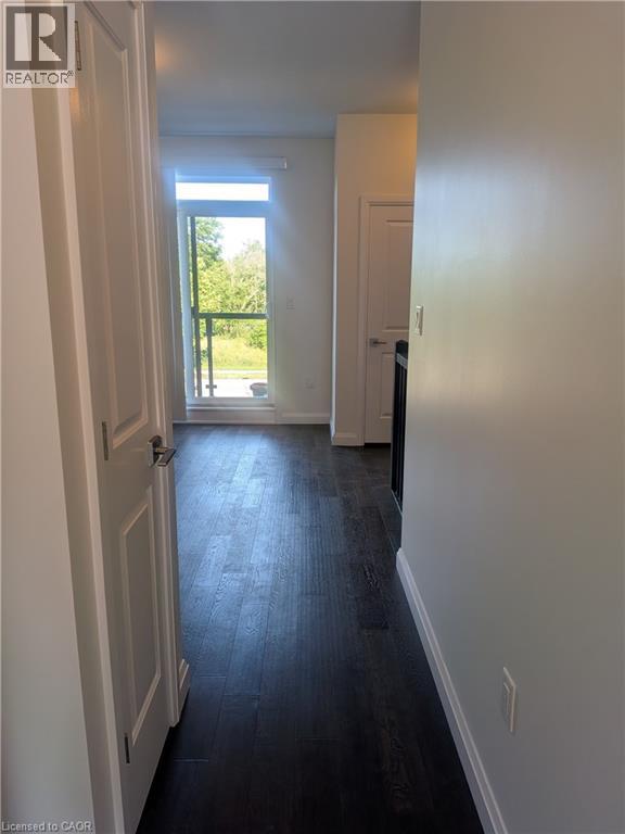 Interior hallway featuring dark wood-finish flooring, white baseboards, and light-toned walls