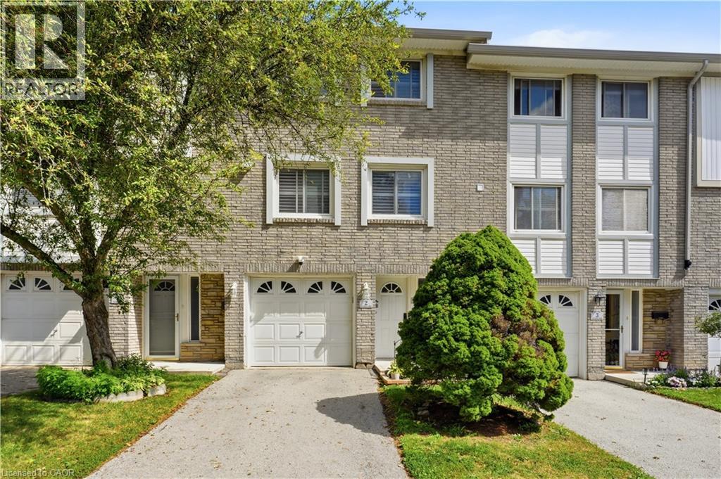 Brick facade with white window trim and white garage doors featuring decorative arched windows